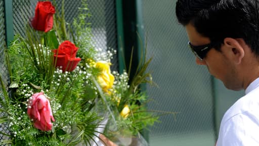 Un homme se recueille devant un bouquet de fleurs, en hommage aux victimes du train.