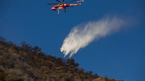 Un hélicoptère de lutte contre les incendies largue de l'eau au-dessus de l'incendie de Hughes à Castaic, un quartier de Los Angeles, en Californie, le 23 janvier 2025.