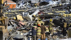 Des équipes de secours au milieu des décombres d'une fabrique de bougies après le passage d'une tornade, le 11 décembre 2021 à Mayfield, dans le Kentucky