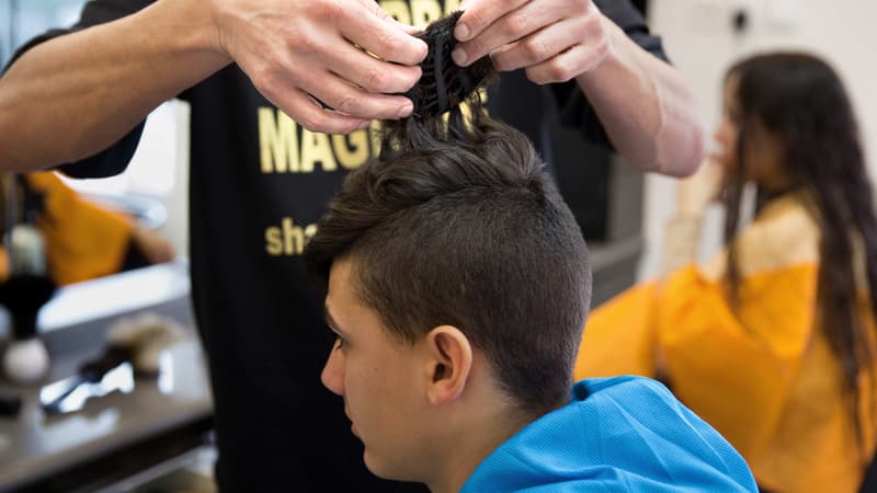 Shalom Koresh accroche une "kippa magique" sur un client de son salon de coiffure de Rehovo, en Israël.