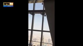 Deux nettoyeurs de fenêtre balancés sur leur nacelles du haut d’un building