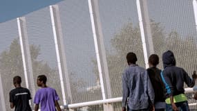 Des migrants marchent à côté d'une clôture bordant la Jungle, à Calais, le 8 septembre 2016.