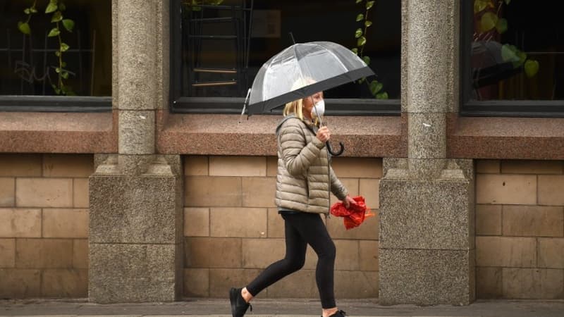 Un femme portant un masque et marchant dans les rues désertes de la ville de Manchester au Royaume-Uni.