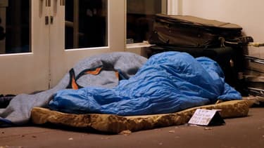 Un SDF se protège du froid dans un sac de couchage, à Paris, en 2012.
