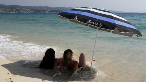 Deux femmes, allongées sur le sable, à l'ombre d'un parasol, sur la plage d'Ajaccio, en Corse
