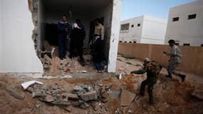 Insurgés libyens près d'une maison touchée par une frappe aérienne à Ras Lanouf, dans l'est de la Libye. Les forces gouvernementales ont poursuivi mardi leurs attaques contre les rebelles, dont les représentants politique ont de leur côté donné 72 heures