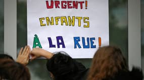 Des enseignants et des bénévoles du DAL (Droit au logement) accrochent une pancarte indiquant "Urgent ! Enfants à la rue" devant l'école primaire Sylvain Dauriac pour alerter sur les conditions de vie de certaines familles dont les enfants fréquentent cette école, à Toulouse, dans le sud-ouest de la France, le 8 décembre 2021. Depuis début décembre 2021, des familles, dont 23 enfants, occupent le gymnase Saint Sernin, à Toulouse. Des associations dont le DAL et des enseignants ont décidé de se mobiliser pour mettre fin à cette situation précaire.