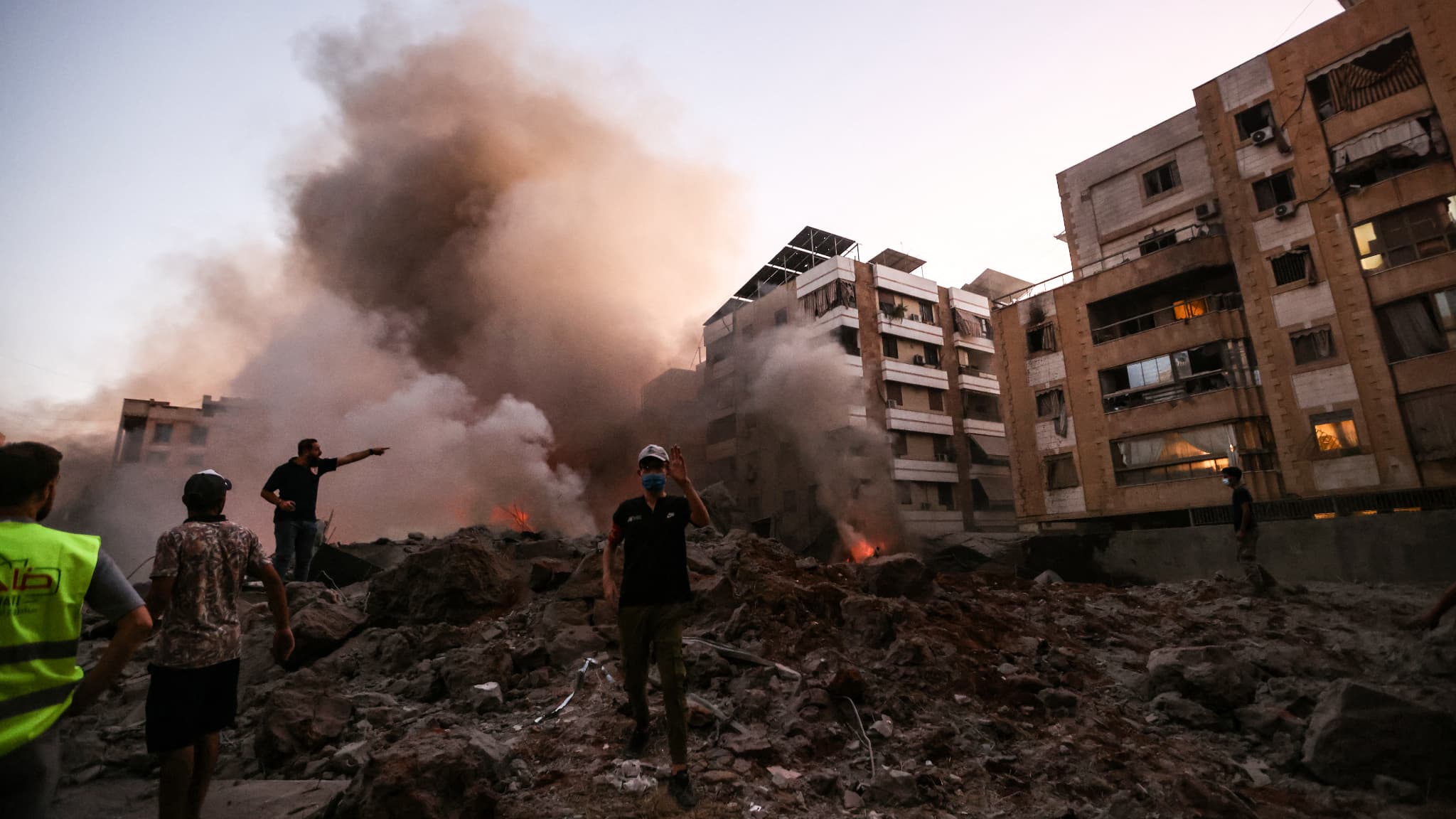 Des personnes et des sauveteurs se tiennent au milieu des décombres d'un bâtiment détruit par une frappe aérienne israélienne dans le quartier de Haret Hreik, dans la banlieue sud de Beyrouth, le 27 septembre 2024. Des personnes et des sauveteurs se tiennent au milieu des décombres d'un bâtiment détruit par une frappe aérienne israélienne dans le quartier de Haret Hreik, dans la banlieue sud de Beyrouth, le 27 septembre 2024.