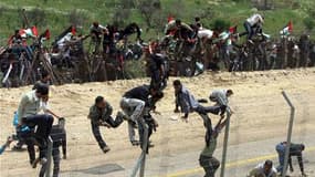 Des manifestants syriens escaladent la barrière à la frontière entre Israël et la Syrie, lors d'un rassemblement à l'occasion de la "Nakba" ou "catastrophe" pour les Palestiniens, qui marque l'anniversaire de la création d'Israël. Des violences ont éclaté