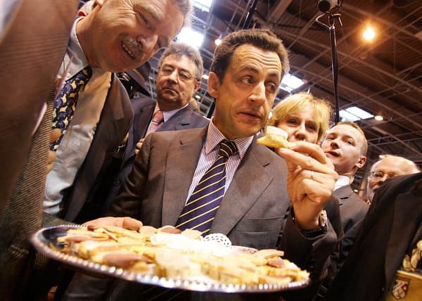 Nicolas Sarkozy, alors ministre de l'Intérieur, goûte du fromage lors du Salon de l'agriculture, le 2 mars 2006.