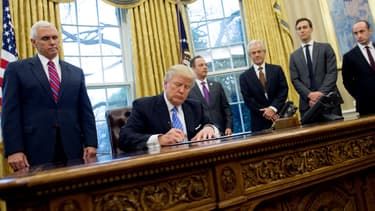 Le président américain Donald Trump signe des décrets entouré de son vice-président Mike Pence, le 23 janvier 2017, dans le Bureau ovale de la Maison Blanche.