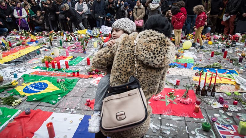 Une mère portant son enfant se recueille en Belgique au lendemain des attentats qui ont frappé Bruxelles.