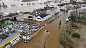 Cette photographie aérienne montre des secouristes à bord d'un aéroglisseur passant devant des entrepôts submergés par les eaux de crue, à Redon, dans l'ouest de la France, le 31 janvier 2025.