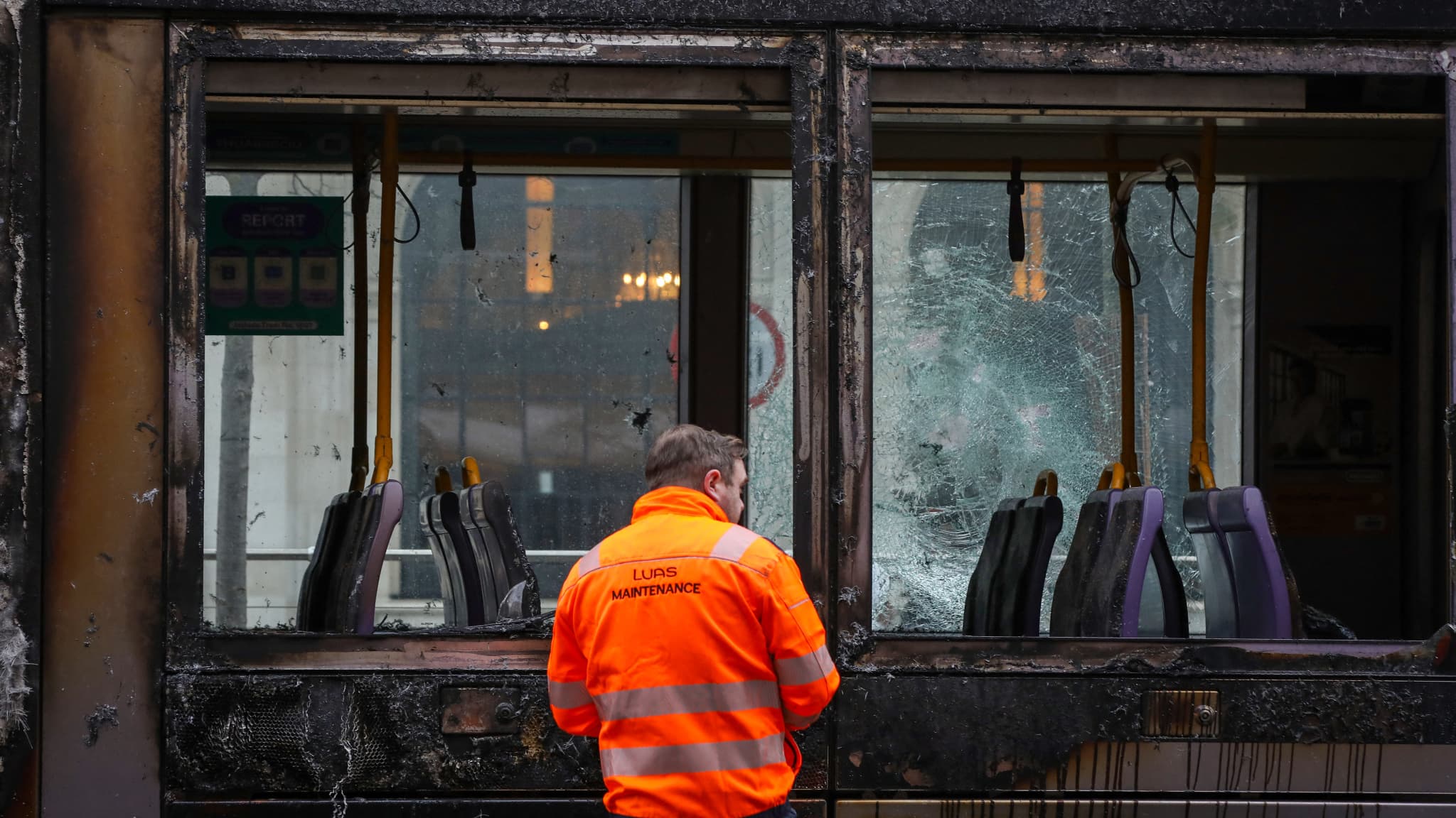 Un ouvrier évalue les dégâts d'un tramway endommagé par le feu à Dublin, le 24 novembre 2023, à la suite d'une nuit de manifestations. Un ouvrier évalue les dégâts d'un tramway endommagé par le feu à Dublin, le 24 novembre 2023, à la suite d'une nuit de manifestations.