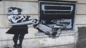 Un tag du graffeur britannique Banksy près d'un distributeur de billets