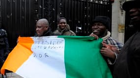 Des partisans d'Alassane Ouattara déploient un drapeau ivoirien devant l'ambassade de Côte d'Ivoire à Paris. Des militants pro-Ouattara ont affirmé lundi avoir pénétré "pacifiquement" dans l'ambassade pour protester contre le maintien au pouvoir du présid