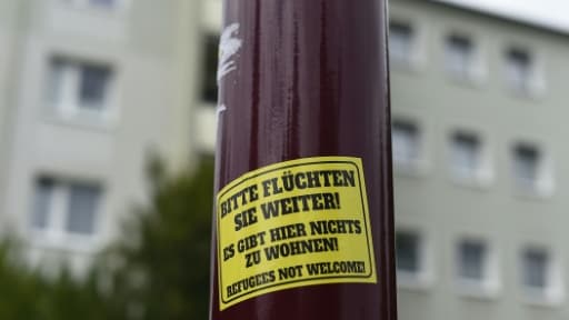 "Nous vous prions de passer votre chemin, il n'y a pas d'endroit où habiter ici, les réfugiés ne sont pas les bienvenus", peut-on lire sur un autocollant collé sur un lampadaire à Freital le 27 juillet 2015 "Nous vous prions de passer votre chemin, il n'y a pas d'endroit où habiter ici, les réfugiés ne sont pas les bienvenus", peut-on lire sur un autocollant collé sur un lampadaire à Freital le 27 juillet 2015