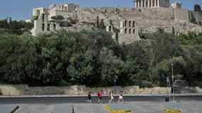 De rares touristes passent au pied de l'Acropole à Athènes, fermée aux heures les plus chaudes de la journée en raison de la "pire canicule" en trente ans en Grèce, le 2 août 2021