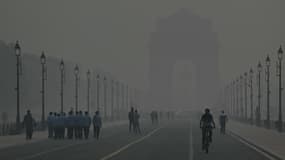 Des personnes marchent dans le brouillard à la Porte de l'Inde, à New Delhi, le 31 octobre 2023. L'ennemi est invisible et il n'y a pas de soldats, mais le nouveau "Green War Room" de la capitale indienne lutte contre la pollution de l'air qui réduit la durée de vie des habitants de plus d'une décennie.