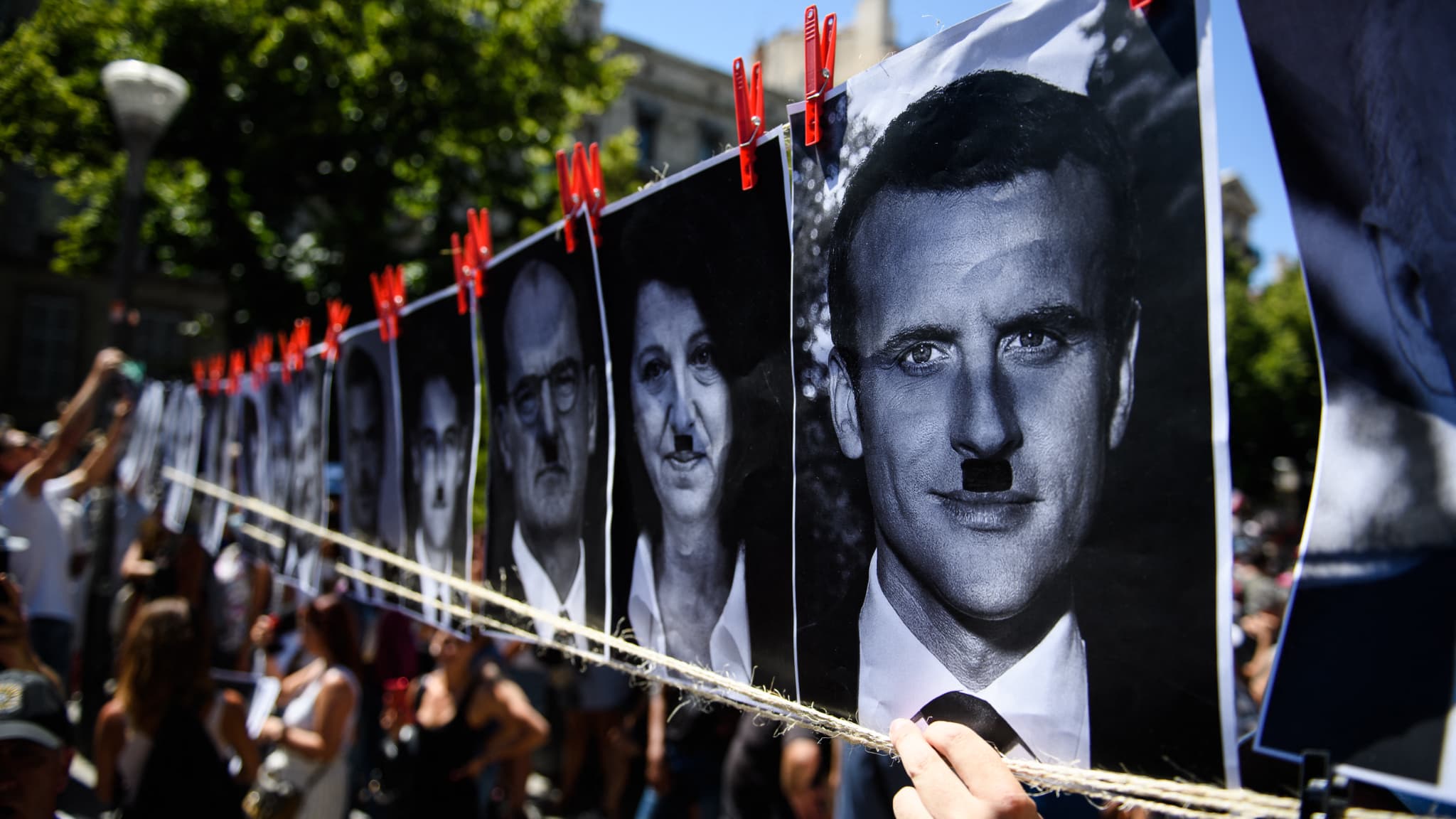 Des portraits d'Emmanuel Macron, Agnès Buzyn ou Jean Castex, retouchés avec la moustache d'Hitler, lors d'une manifestation à Marseille, le 17 juillet 2021. Des portraits d'Emmanuel Macron, Agnès Buzyn ou Jean Castex, retouchés avec la moustache d'Hitler, lors d'une manifestation à Marseille, le 17 juillet 2021.