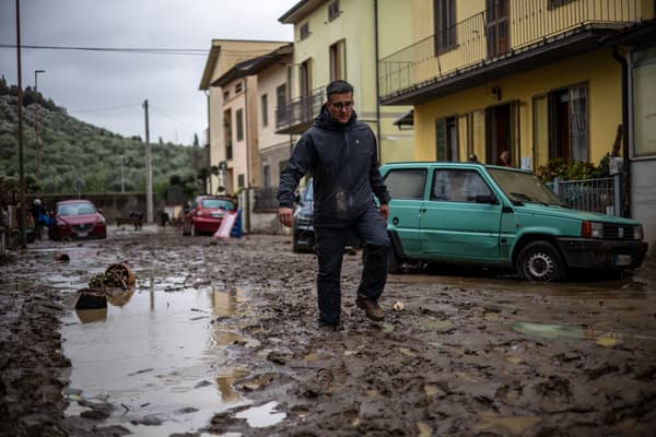 Un homme marche dans une rue boueuse de Montemurlo, à côté de Prato, en Toscane (Italie), le 3 novembre 2023 après le passage de la tempête Ciaran