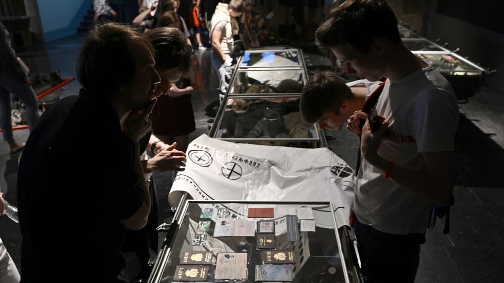 Des visiteurs observent des passeports russes exposés dans l'exposition "Ukraine - Crucifixion", présentée à Kiev, le 4 juin 2022.