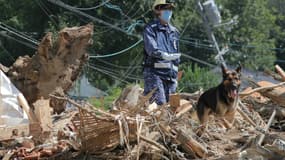 Un sauveteur et son chien à la recherche de disparus dans les décombres à Kure, dans la préfecture d'Hiroshima , le 12 juillet 2018