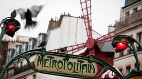 Une photo prise le 12 janvier 2011 montre des pigeons posés sur un panneau du métro devant le Moulin Rouge dans le quartier de Pigalle à Paris.
