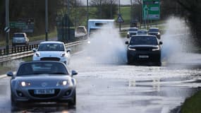 Des voitures roulent sur une route inondée près de Cirencester, dans l'ouest de l'Angleterre, le 3 janvier 2024, à la suite de la tempête Henk.