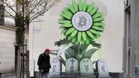 Une peinture de l'artiste Ludo montre le logo du Bitcoin au-dessus des tombes des monnaies traditionnelles, comme le dollar et l'euro. 