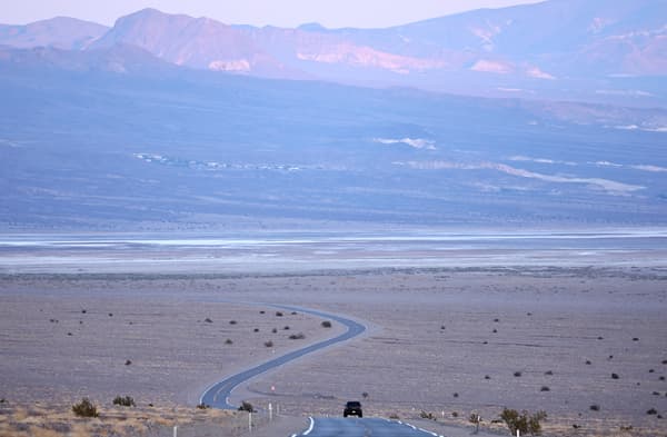  Un véhicule roule avant le coucher du soleil pendant une vague de chaleur de longue durée qui touche une grande partie de la Californie, le 8 juillet 2024, dans le parc national de la Vallée de la Mort, aux États-Unis.