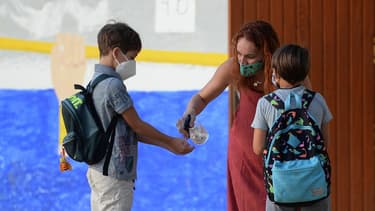 Une enseignante en train de désinfecter les mains d'un élève dans une école près de Séville.
