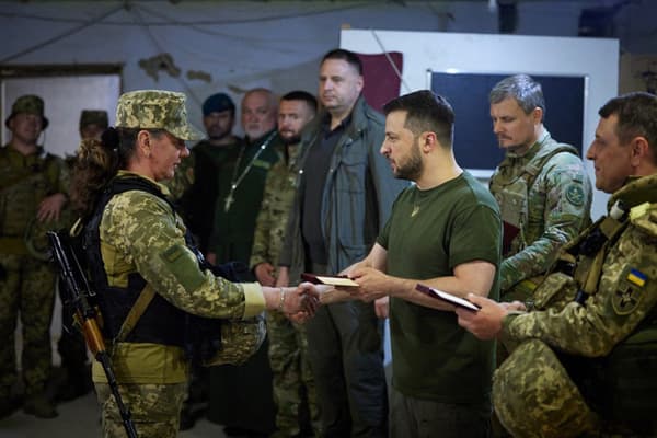 Le président ukrainien Volodymyr Zelensky remet une récompense à une combattante ukrainienne lors de sa visite à Mykolaïv dans le sud du pays le 18 juin 2022. 