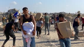Des hommes regardent autour d'eux, en état d'alerte, suite à des coups de feu, alors que des Palestiniens déplacés reçoivent des paquets de nourriture d'une fondation soutenue par les États-Unis, dans le sud de la bande de Gaza, le 27 mai 2025.