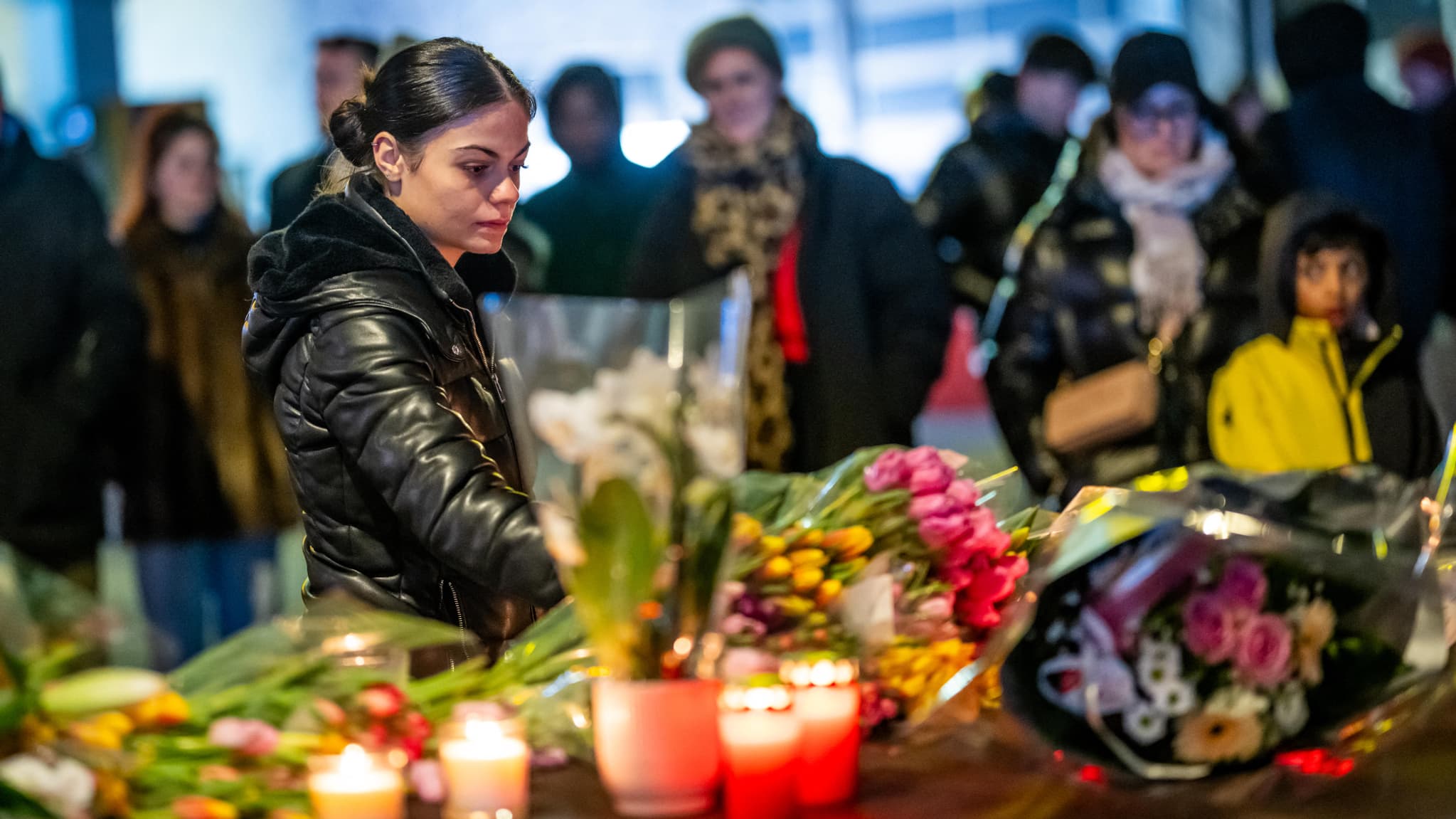 Des personnes en deuil se rassemblent devant des fleurs et des bougies déposées près du lieu où un incendie a ravagé un bar bondé lors des célébrations du Nouvel An à Crans-Montana, station de ski alpine, le 1er janvier 2026.