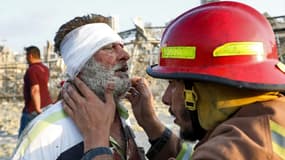 Un pompier portant secours à un homme blessé après les explosions survenues à Beyrouth.
