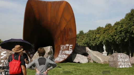 Des visiteurs s'arrêtent devant une des  œuvres de Anish Kapoor vandalisée par des tags antisémites, dans les jardins du Château de Versailles le 11 septembre 2015