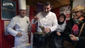 Les chefs Emile Jung (à gauche) et Pascal Bastian (centre) servent une tasse de soupe au marché de Noël de Strasbourg, le 27 novembre 2015.