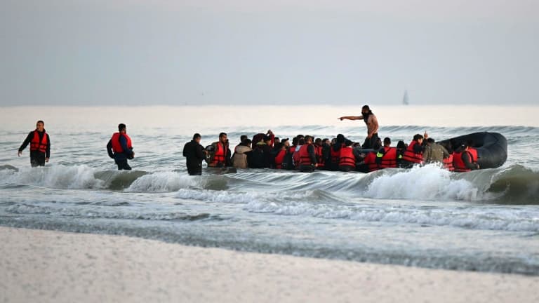 Un passeur (c) debout parmi des migrants à bord d'un bateau pneumatique pour tenter de traverser illégalement la Manche vers la Grande-Bretagne, le 11 juillet 2022 près de Gravlines, dans le Nord