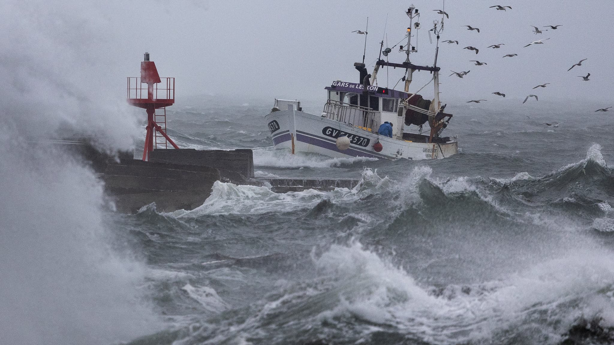 Un bateau de pêche arrive au port de Plobannalec-Lesconil, dans l'ouest de la France, le 22 octobre 2025, alors que d'énormes vagues et des vents violents frappent la côte lors du passage de la tempête Benjamin.