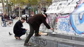 Des personnes posent des fleurs et des bougies face au monument de la Place de la République, le 14 novembre 2015 à Paris