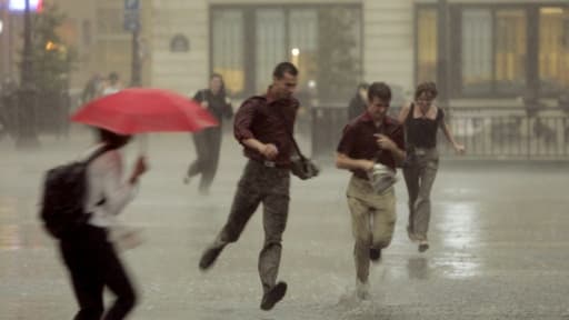 Des personnes courent dans les rues de Paris afin de se mettre à l'abri de la pluie lors d'un orage le 23 juin 2005