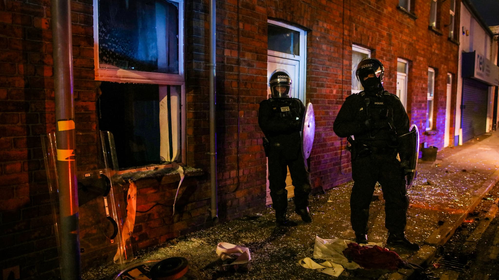 Des policiers se tiennent devant une maison attaquée lors d'une manifestation anti-immigration à Ballymena, en Irlande du Nord, le 10 juin 2025.