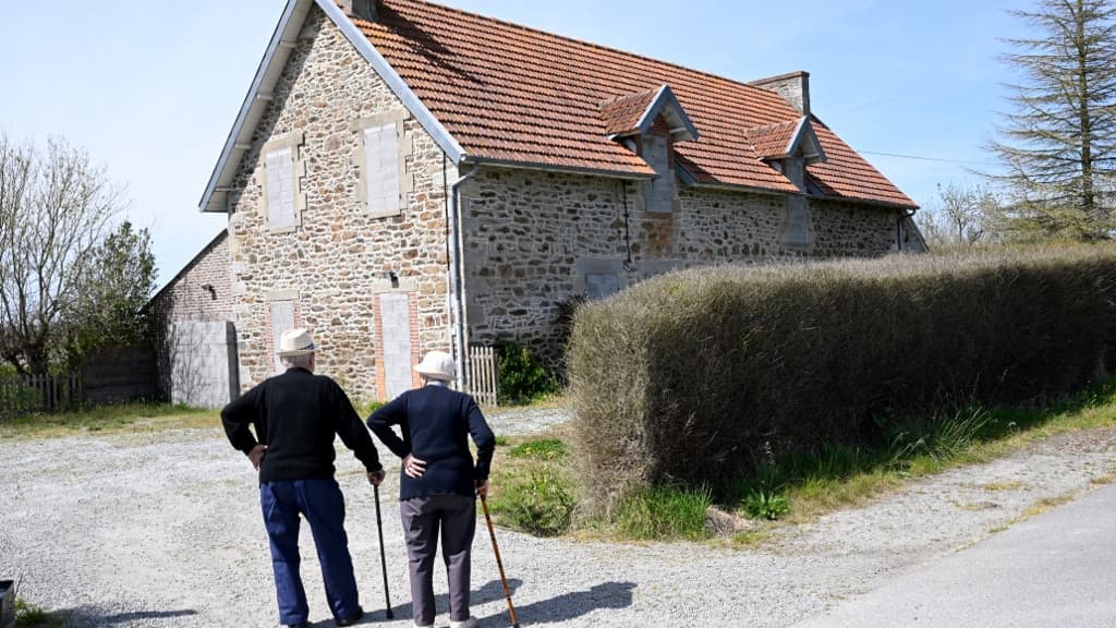 Deux personnes devant une maison condamnée par la future montée des eaux, près d'une digue à Lancieux, dans l'ouest de la France, le 5 mai 2022.