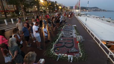 Des gens se rassemblent autour d'un mémorial de fortune le 14 juillet 2017 sur la "Promenade des Anglais" à Nice, dans le sud de la France, après une cérémonie commémorative marquant le premier anniversaire de l'attaque d'un camion jihadiste qui a tué 86 personnes le 14 juillet 2016