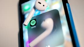 Des écouteurs sur un iPhone montrant le logo de Spotify.