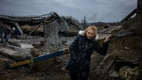 Une femme prend un peu de repos après avoir traversé un pont déruit pour quitter la ville d'Irpin, au nord-ouest de Kiev, le 7 mars 2022