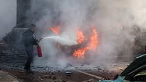 Un membre des forces de sécurité israéliennes tente d'éteindre des voitures en feu après une attaque à la roquette depuis la bande de Gaza à Ashkelon, dans le sud d'Israël, le 7 octobre 2023