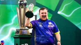 Luke Littler soulevant son trophée de vice-champion du monde de fléchettes