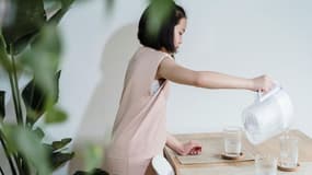 Une jeune fille versant de l'eau avec une carafe filtrante (photo d'illustration).